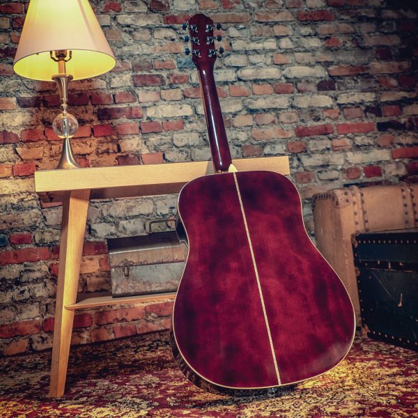back of Oscar Schmidt acoustic guitar leaning against small table