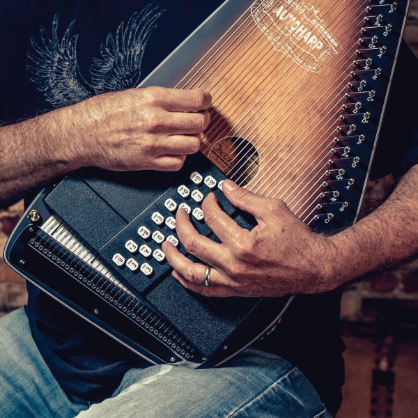 man's hands playing Oscar Schmidt Autoharp