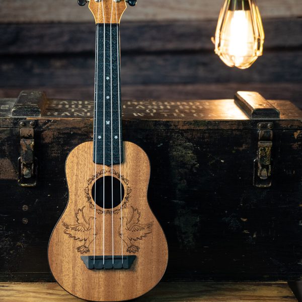Oscar Schmidt ukulele with dove design in front of chest